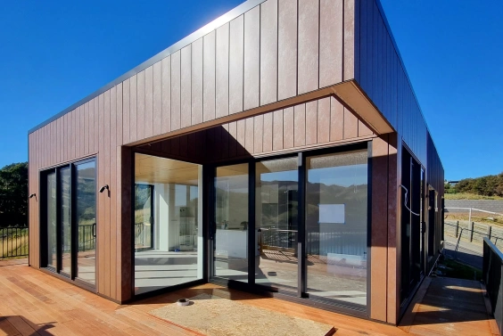 A modern residential home featuring Interlocking cladding in Corten Rust color, blending harmoniously with the wooden deck and natural surroundings.