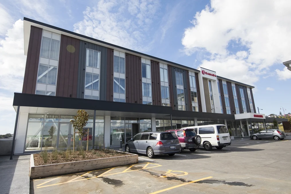 A modern hotel with mixed cladding materials, including dark steel panels and large glass windows.