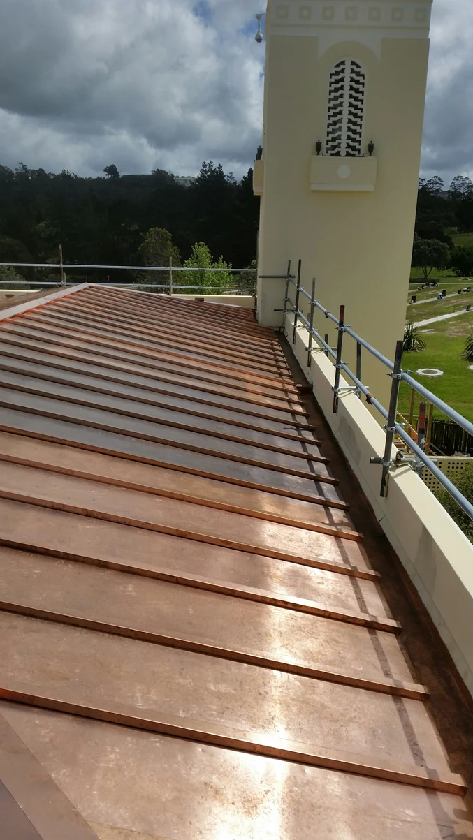 A close-up view of a roof with copper-toned steel batten caps, showcasing intricate craftsmanship.