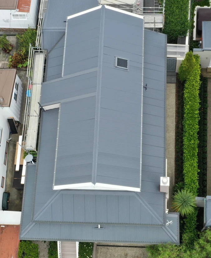 Aerial view of a residential roof with a clean grey finish and precise geometric design.