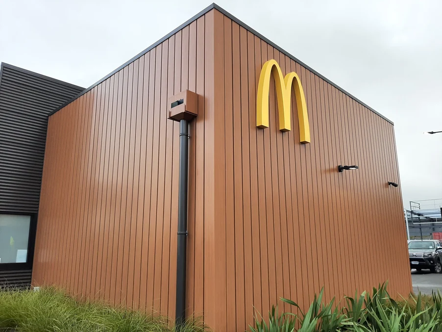 A McDonald's outlet with brown vertical steel cladding and modern landscaping.