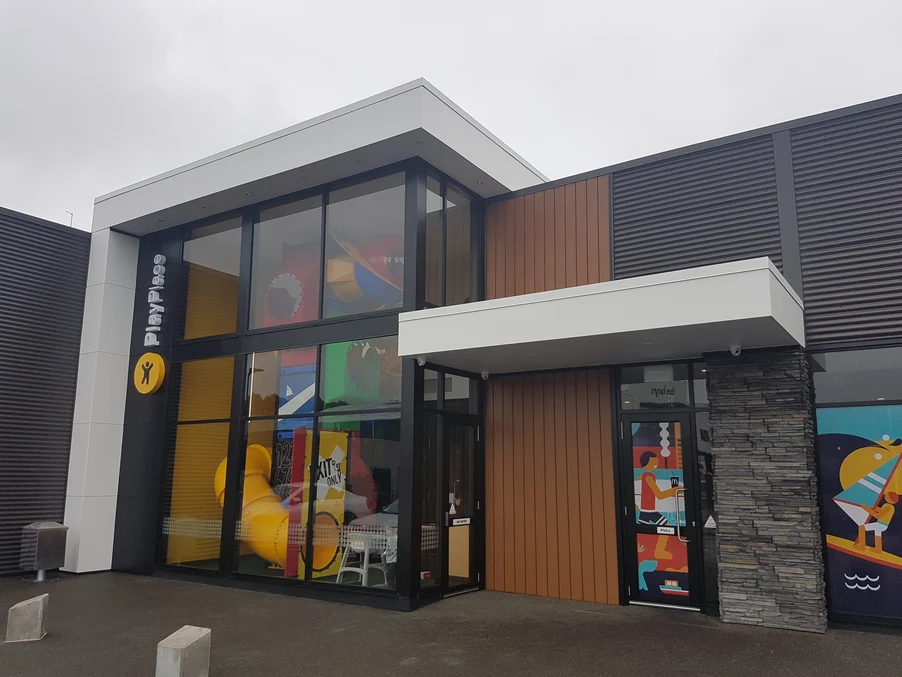 A modern retail space with a mix of brown cladding, white panelling, and stone features.