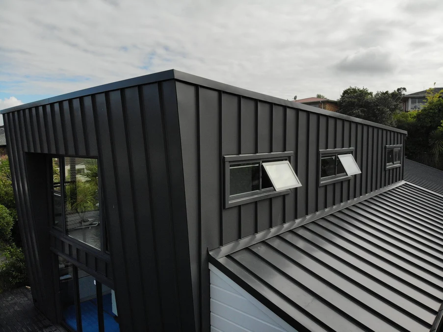 Close-up of a contemporary building with black standing seam cladding and roofing.