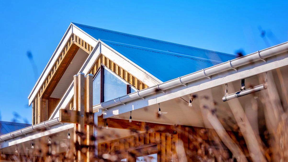 A community pub in Canterbury with a modern steel roof and timber accents, set against a bright blue sky.