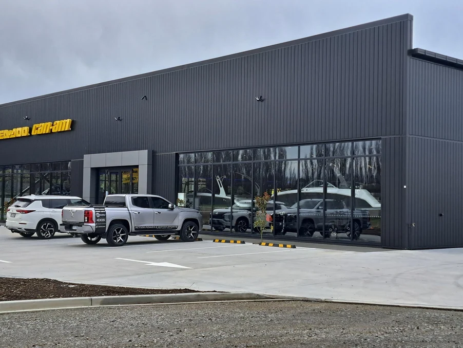 A commercial retail facility with black vertical steel cladding and glass storefronts.